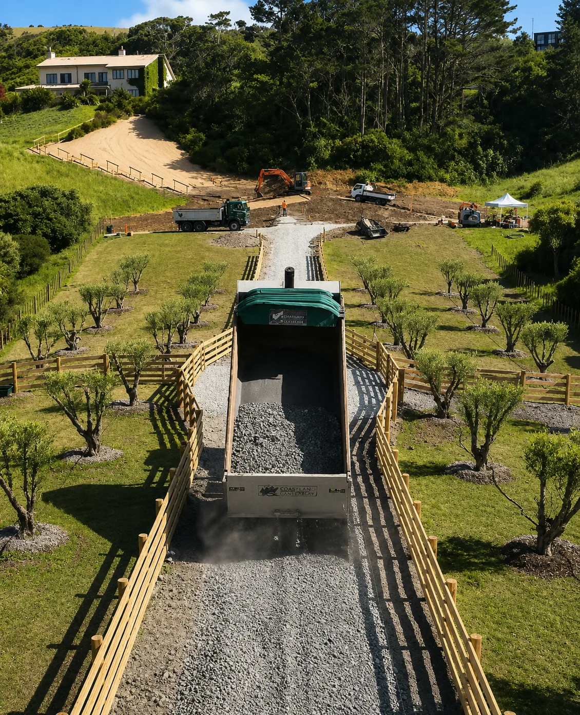 Truck laying gravel on a new driveway during early-stage landscape construction