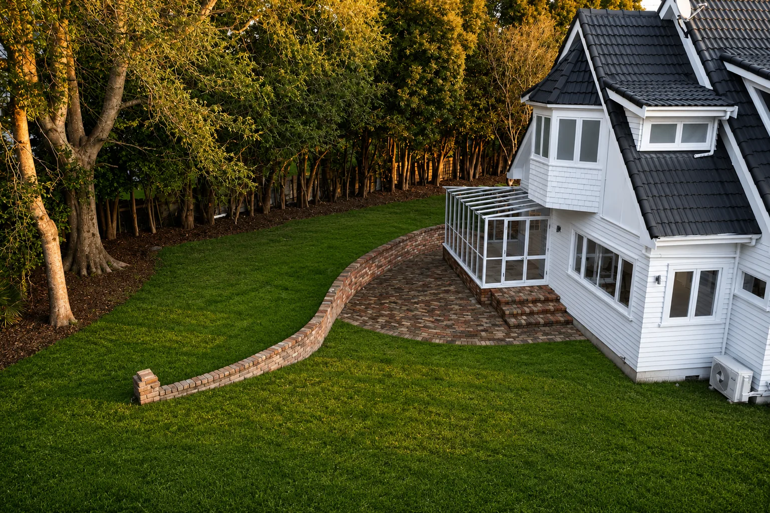 Brick patio and curved retaining wall alongside the home