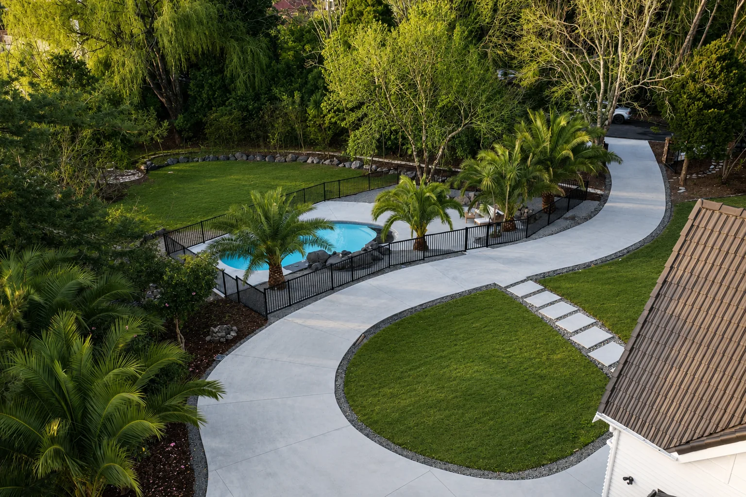 Curved concrete driveway with pool and palm plantings