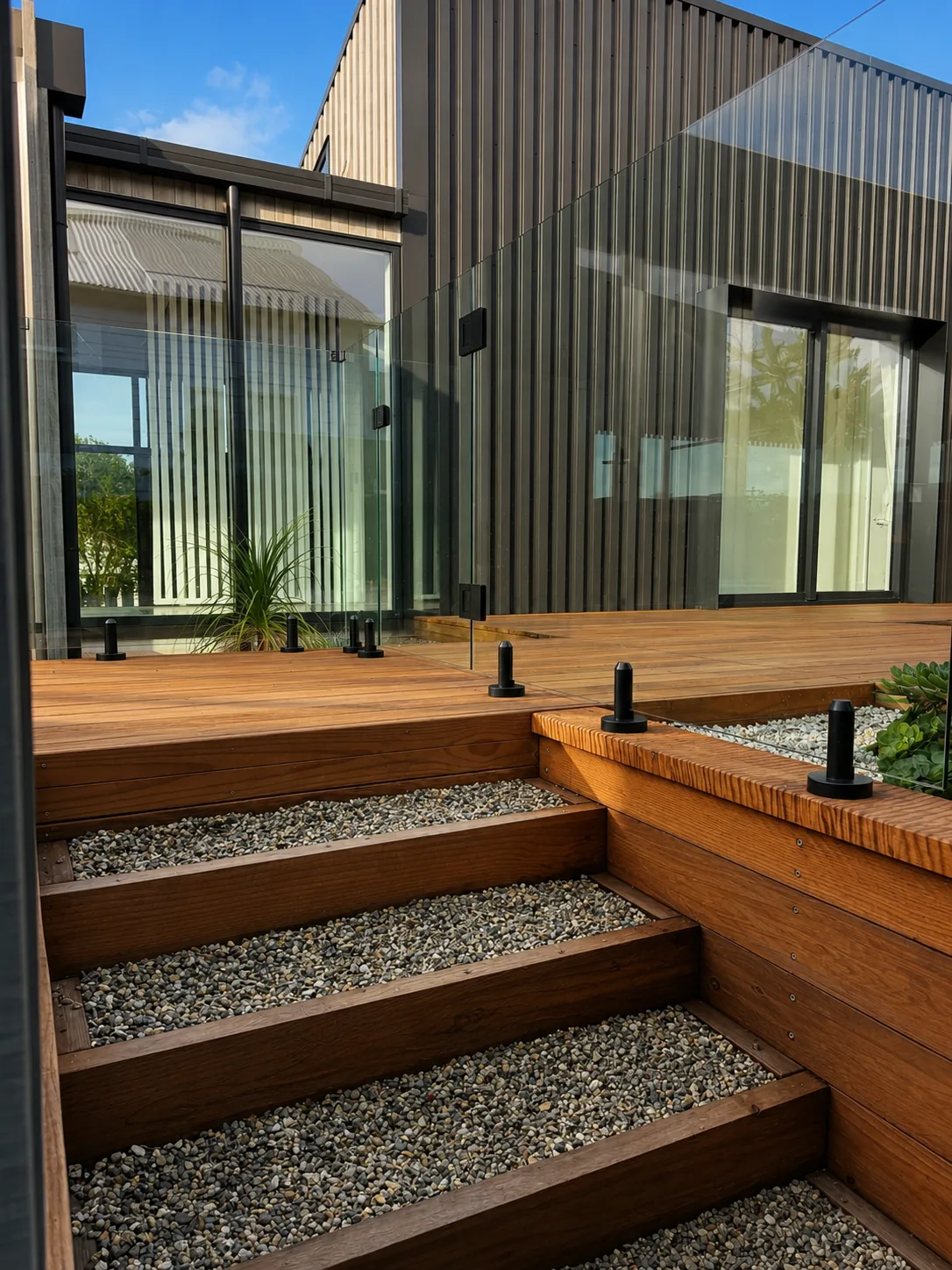 Gravel timber steps leading to the raised deck and glass balustrade