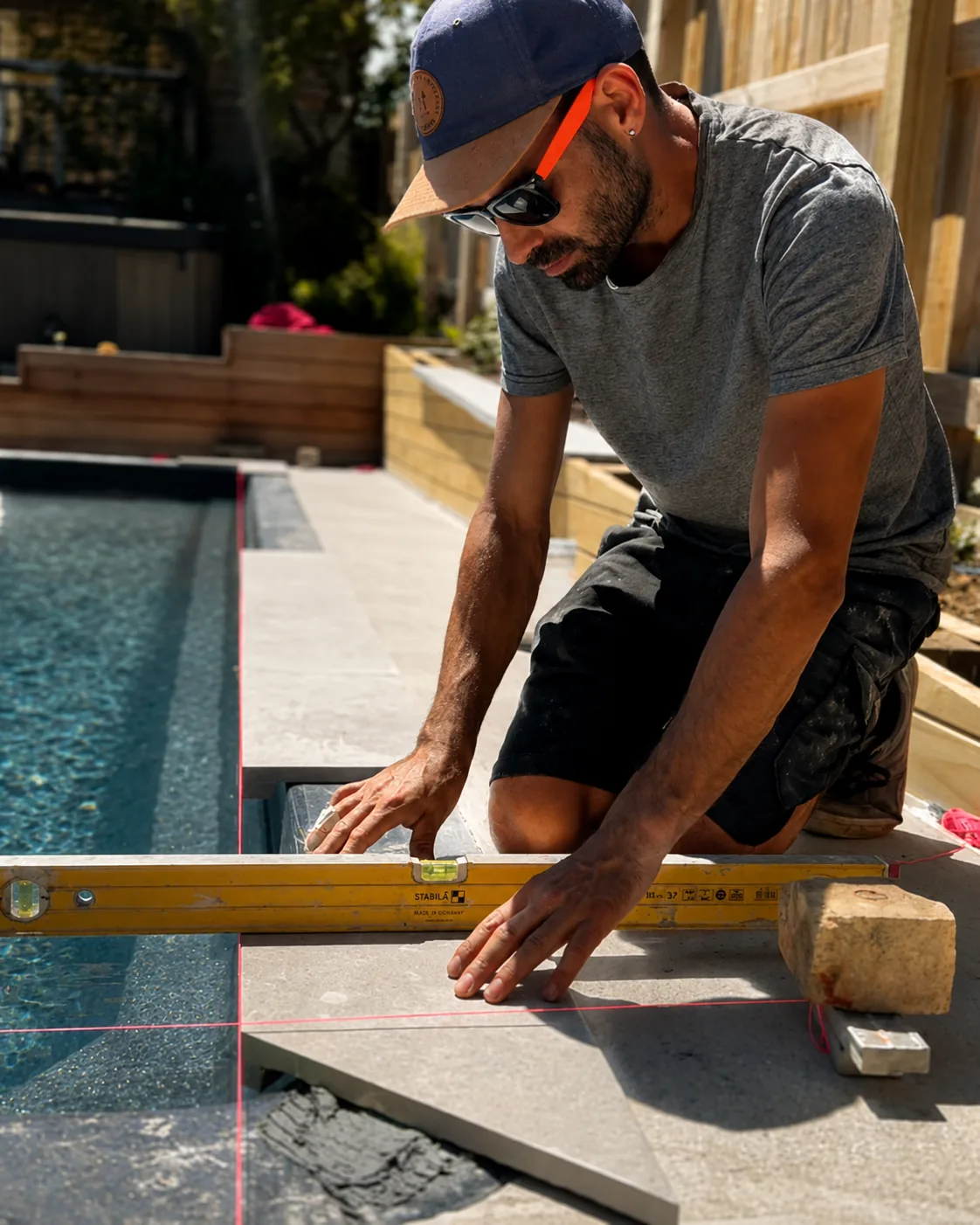 Levelling stone pavers along the pool edge at Kia Ora Road